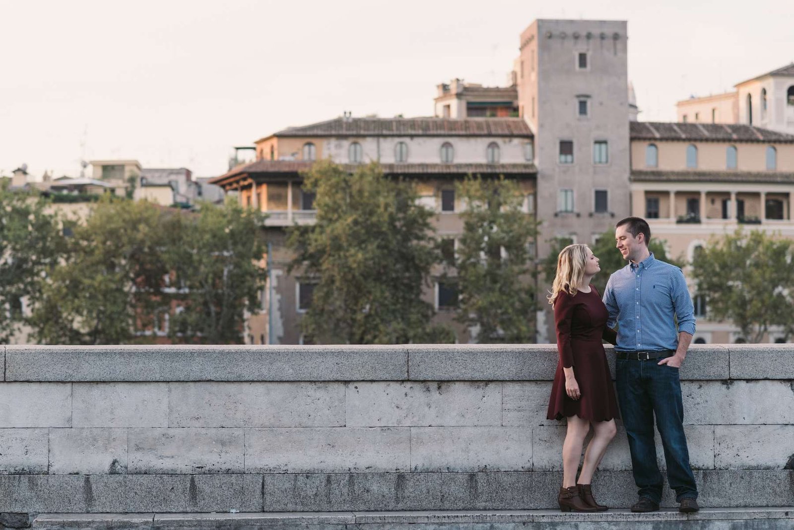 A couple on the Tiber embankment with rooftops behind
