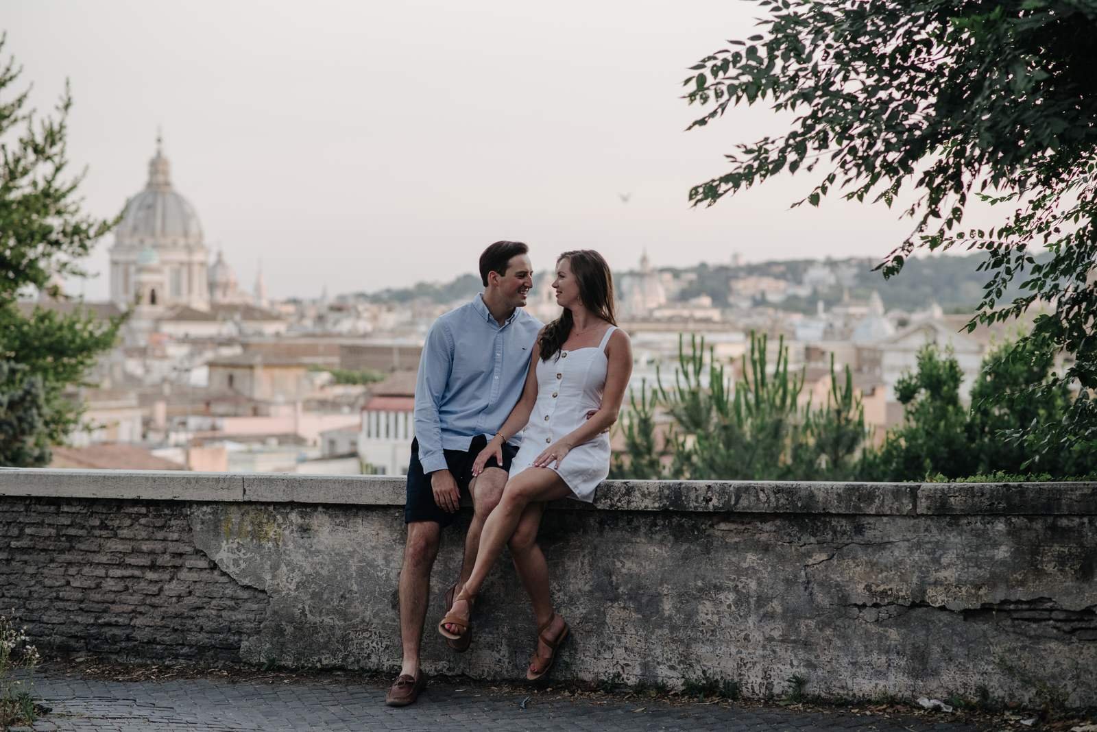 A couple sitting on the terrace wall with the dome behind